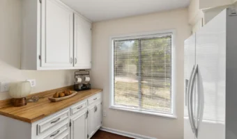 Bright compact kitchen with white cabinets and light walls
