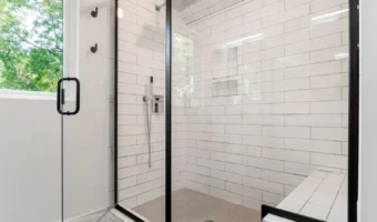White tiled shower walls behind a glass enclosure